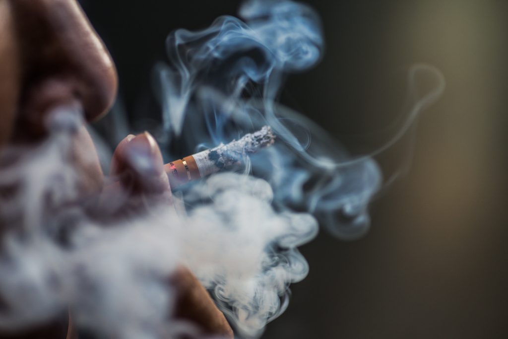 closeup-shot-person-puffing-cigarette-surrounded-with-smoke